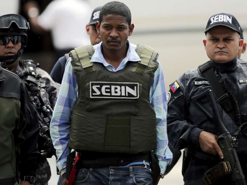 Leiver Padilla Mendoza (C), alias "El Colombia", is escorted by police officers as he arrives to Venezuela, after being extradited from Colombia, at Simon Bolivar Airport in Caracas May 30, 2015. Padilla Mendoza is accused of the murder of Venezuelan legislator Robert Serra, according to local media. REUTERS/Marco Bello